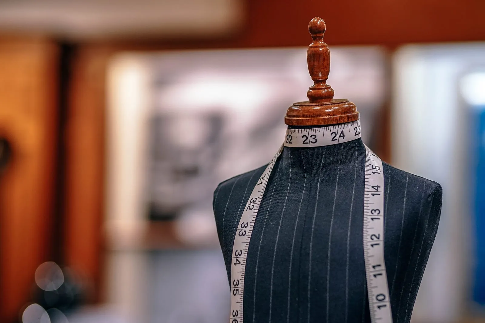 A pinstriped tailor's dress form with a measuring tape draped around the neck
